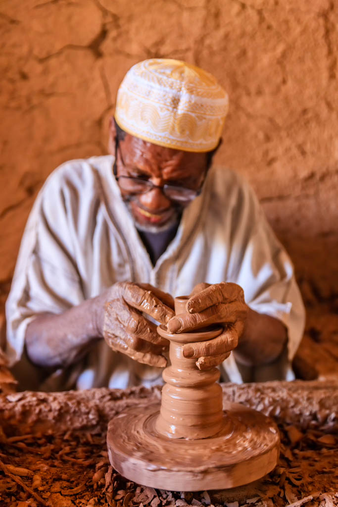 "Moroccan potter working in the workshop on the pottery wheel near Ouarzazate, Morocco."
